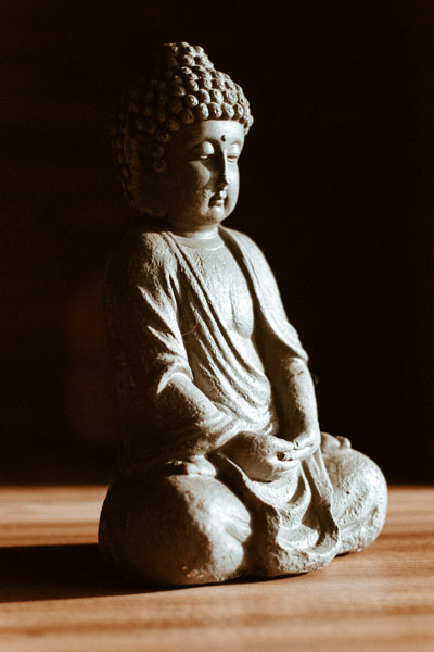 Une statue de bouddha en position de méditation dans un rayon de lumière.